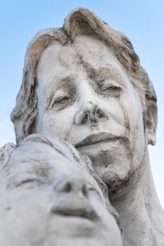 Statue of a mother and son against blue sky