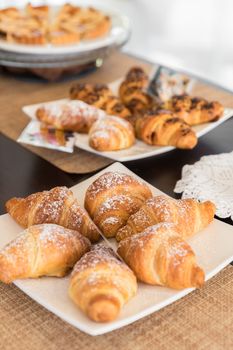 Selection self service continental breakfast buffet display, catering or brunch table food buffet filled with delicious croissants and homemade cakes in a hotel or restaurant setting.