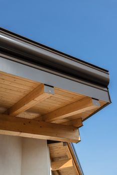 New wooden warm ecological house roof with steel gutter rain system. Professional construction and drainage pipes installation. Eco materials.