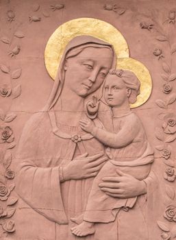 Sculpture in Bas - relief in red stone of Mary and baby Jesus, with golden crowns. Ideal for concepts, events and backgrounds.