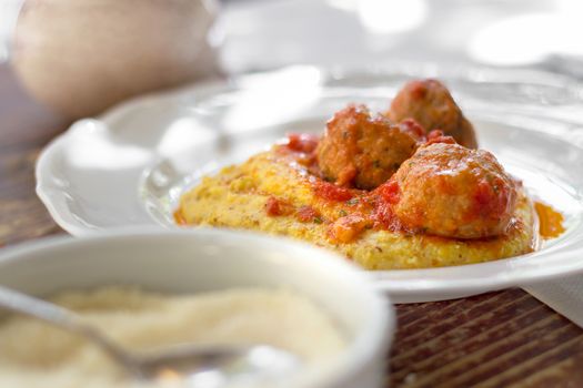 Traditional italian pork and beef meatballs served on polenta with tomato sauce, basil, parmesan and a drizzle of olive oil.