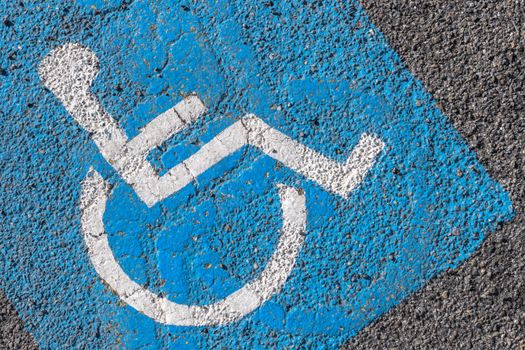 Close - up of disabled parking sign painted on tarmac. Ideal for concepts and backgrounds.
