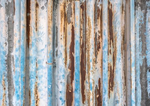 Old corrugated metal texture with rust spots on surface and peeled-off paint.