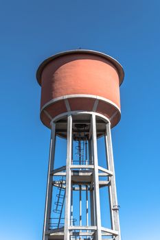 Water tower tank, providing a rural area with fresh water, from high above, under an expansive blue sky.