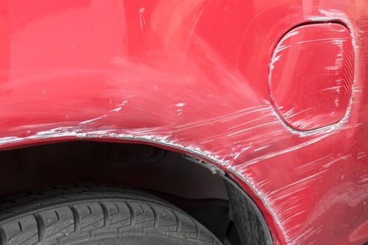 Scratches on the side of the red car. Collision or accident.