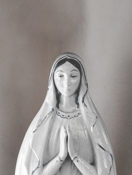 Virgin Mary porcelain statue in a vintage background