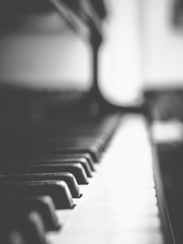 Close-up of piano keys with blurred background. Vintage style photo with scratches, dust, grain and dirt. One key in focus.