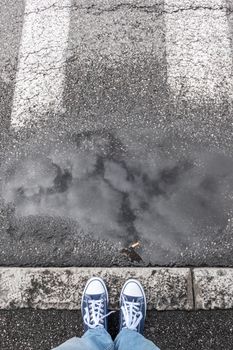 Feet of a man in sneakers shoes standing on gray sidewalk. Ideal for concepts.