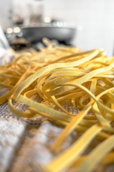 Freshly prepared Tagliatelle pasta closeup. Pasta fettuccine with wheat. Selective Focus. Defocused blurry background.