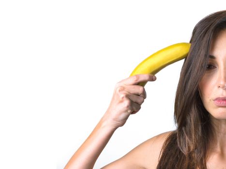 Woman holds a banana near her head in the manner of a revolver. Space for text.