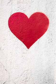 Red love heart hand drawn on grungy wall. Textured background trendy street style. Copy space.