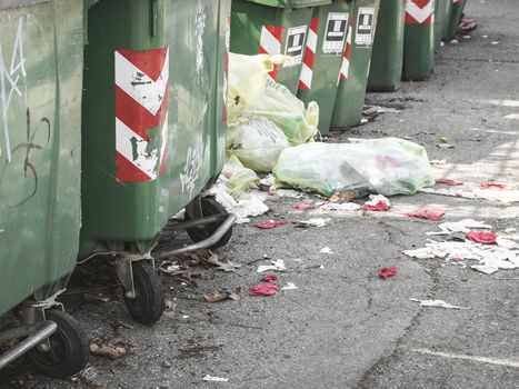 Abandoned garbage. Trash cans standing in a row ready to be collected on a residential street. On the ground, garbage bags that create pollution and dirt.