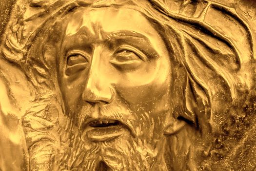 Golden bas-relief of Jesus crowned with thorns. High golden relief face of Jesus Christ with crown of thorns.