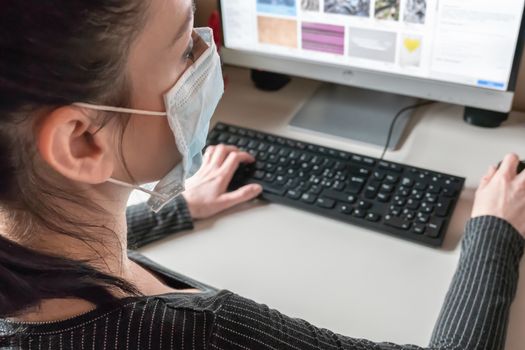 Young business woman working from home wearing protective mask. Coronavirus. Business woman in quarantine for coronavirus wearing protective mask. Working from home.