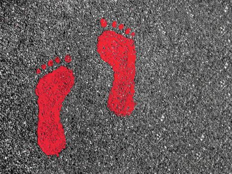 Red footprint signs on an asphalt road for pedestrian. Symbol of walkway.