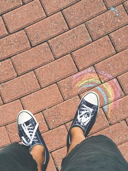Sneakers on the road with a rainbow drawn. Spring and summer concept. Outdoor ideas and creativity.