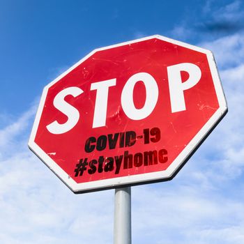 Grungy stop sign with hashtag #stayhome (COVID-19) on sky background. Coronavirus in Italy. COVID-19 alert banner. 2019 Coronavirus concept for an outbreak occurs in Wuhan - China.