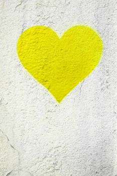 Yellow love heart hand drawn on grungy wall. Textured background trendy street style. Copy space.