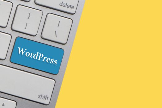 WORDPRESS text on keyboard over yellow background. Business and technology concept