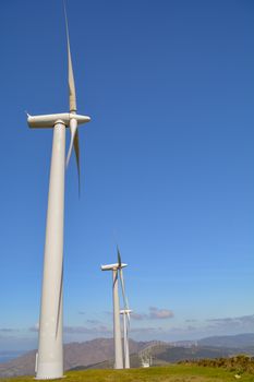 Landscape with lined up wind turbines of a wind farm on a mountain rig. Sustainable energy