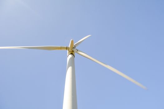 Close-up and low angle view of spinning blades of a wind turbine generating renewable and low carbon energy