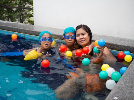 A portrait of a mother and son playing ball in the pool.