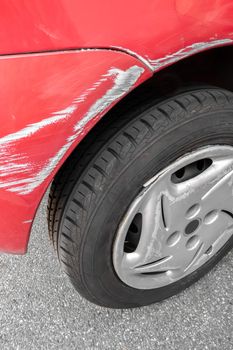 Car body damage. Dents and scratches on the red car paint.