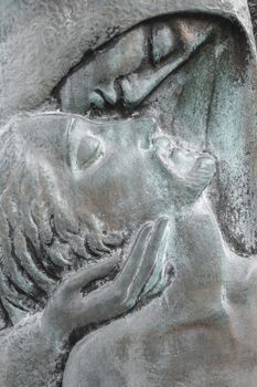 Bronze relief of dead Jesus Christ down from the cross and the Virgin Mary. Easter and religion thematics.