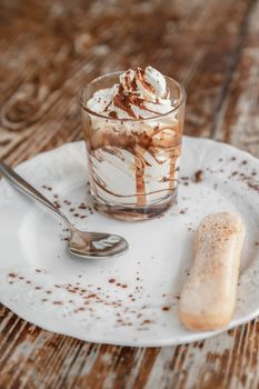 Traditional italian dessert tiramisu in a glass on dark rustic table
