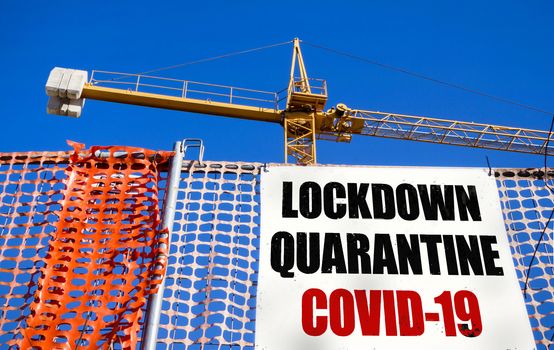 Billboard on the construction site with message LOCKDOWN QUARANTINE COVID-19. COVID-19 alert concept. Lockdown. Concept of stop working activities due to coronavirus medical emergency.