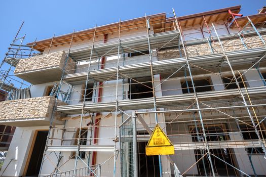 Scaffolding near a house under construction for external plaster works. Modern apartment building in city with stone balconies.