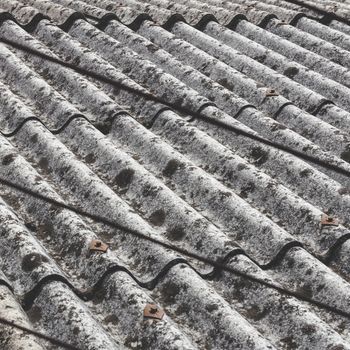 Old and dangerous asbestos roof, one of the most dangerous materials in the construction industry. Eternit roof covering of a scruffy old and moldy.