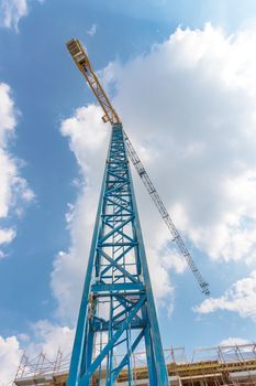 Rise building with cranes under construction. Building construction site against blue sky With clouds. Bottom view.