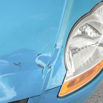Damaged bodywork. Dents and scratch marks on a car's hood. Close-up.