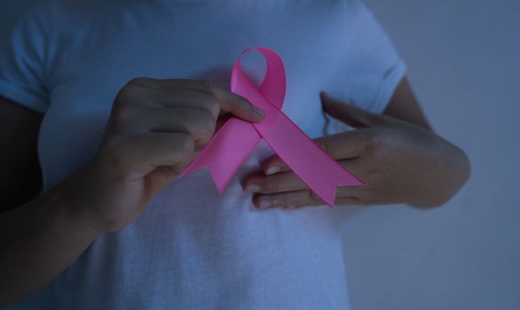 A woman with a pink ribbon on breast cancer awareness Health care and medical concept isolated on pink background.