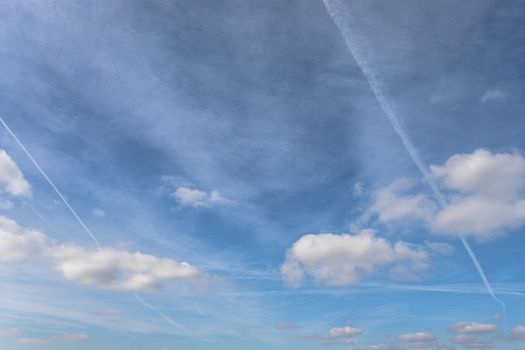 Jet trails, known as chemtrails or contrails over blue sky background with glazes.