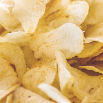 Yellow salted potato chips as background. Crispy chips golden pattern.