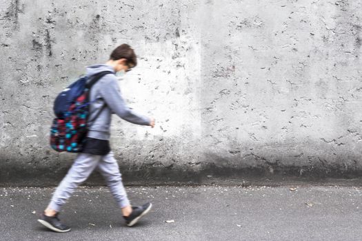 Schoolboy wearing face mask during coronavirus outbreak. Boy going back to school after covid-19 quarantine. Boy in safety mask for coronavirus prevention. Kid with backpack going to school.