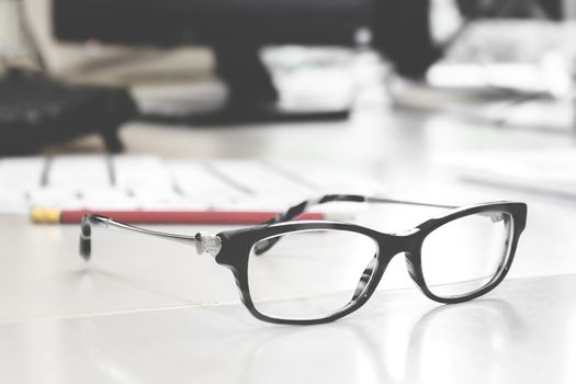 Glasses on the desk in an office. Blurred background. Ideal for Business and finance concept of office working.