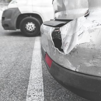 Damaged car. Road accident. Back of gray car get damaged from accident on the road. Vehicle bumper dent broken by car crash. Retro style photo.