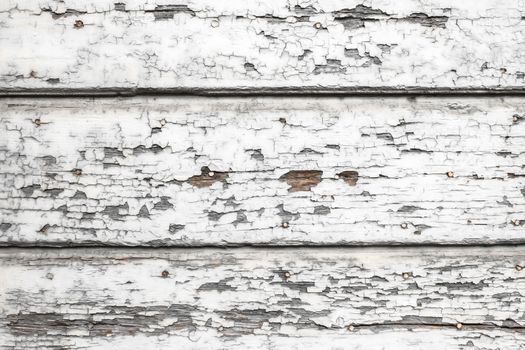 Old wooden painted white rustic fence, paint peeling background.