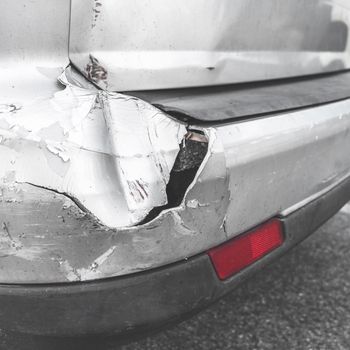 Damaged car. Road accident. Back of gray car get damaged from accident on the road. Vehicle bumper dent broken by car crash. Retro style photo.