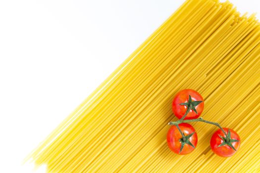 Spaghetti and cherry tomato. Uncooked spaghetti and cherry tomato on white background. Top view with copy space.