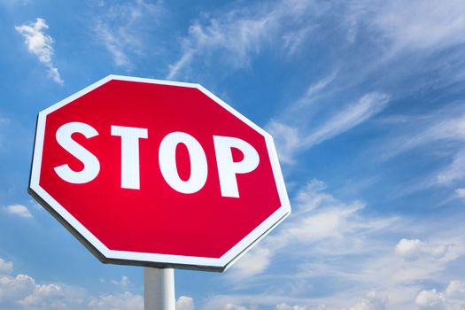 Stop sign against blue cloudy sky