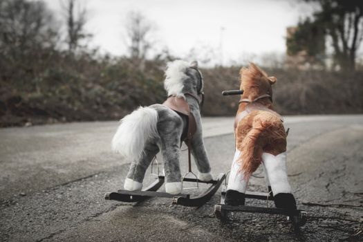 Abandoned rocking horses on the road. Concept of abandonment, loneliness, the end of childhood.