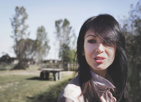 Country girl in retro style photo. Young country girl hints at a smile, looking far.