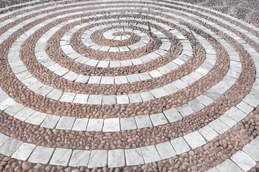 Pebbles mosaic floor with spiral pattern. Ornament out of white and pink cobbles.