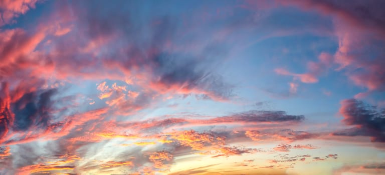 Beautiful panorama of orange and yellow clouds at sunrise and sunset in a blue sky