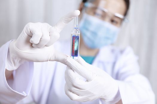 Covid-19 coronavirus vaccine. Close up hands of scientist show Covid-19 vaccine in glass vial. Hands of doctor wear latex glove holding Covid-19 vaccine in glass vial. Healthcare and medical concept.
