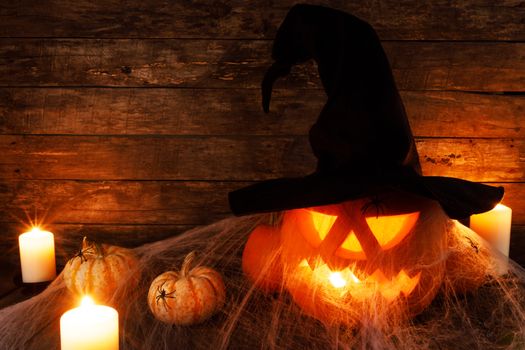 Jack O Lantern Halloween pumpkin with witches hat , spiders on web and burning candles